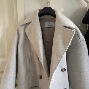 Beige kappa från Stradivarius - Säljer en stilren beige kappa från Stradivarius. Den har en klassisk design med breda slag och knappar framtill. Perfekt för att hålla stilen under kyligare dagar. 🧥✨