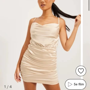 Champagnefärgad kort klänning - Snygg champagnefärgad kort klänning i satin med smala axelband och draperad design. Perfekt för en kväll ute eller en speciell tillställning. Klänningen har en figurnära passform som framhäver dina kurvor. Skriv för bild på klänningen jag säljer. 