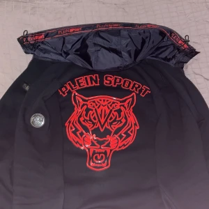 Svart jacka från Plein Sport - Tjena jag säljer min snygga mörkblåa hoodie/jacka från Plein Sport som är philip pleins sport kategori. Köptes för ungefär 1 år sedan och har använts då och då. Den har inga skador eller liknande då jag har tagit hand om den. Ny pris är ca 5500kr, priset är inte fast och förhandling är möjligt. Det är storlek S och är bra i storleken. Kan frakta och mötas upp men då är det i västra Frölunda Göteborg. Om du har någon fundering är det bara att höra av sig😀