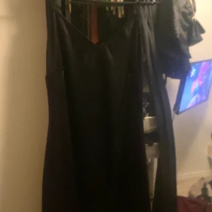 Svart långklänning - Elegant svart långklänning med en stilren design. Perfekt för festliga tillfällen. Klänningen har en vacker fall och är tillverkad i ett mjukt material som ger en fin siluett.