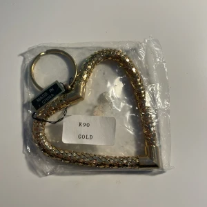 Guld hjärtformat nyckelring - Snygg nyckelknippa i form av ett hjärta. Armbandet har en flätad design som ger din väska exp jättesnygg! Har inte and vänt så jag är silver tyvärr!!