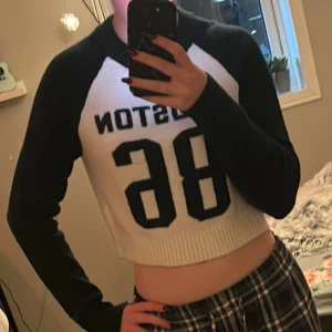 Svart och vit  croppad ull tröja från FB Sister - Säljer en cool croppad ull tröja från FB Sister med texten 'Houston 86' på framsidan. Tröjan är svart och vit med långa ärmar och ribbad nederkant. Perfekt för en avslappnad stil.