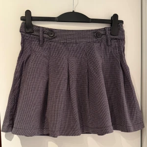 Grå rutig kortkjol med knappar - H&M L.O.G.G. - Snygg grå rutig kortkjol med knappar och dragkedja i sidan. Kjolen har en klassisk design med veckad nederdel och bälteshällor i midjan. 