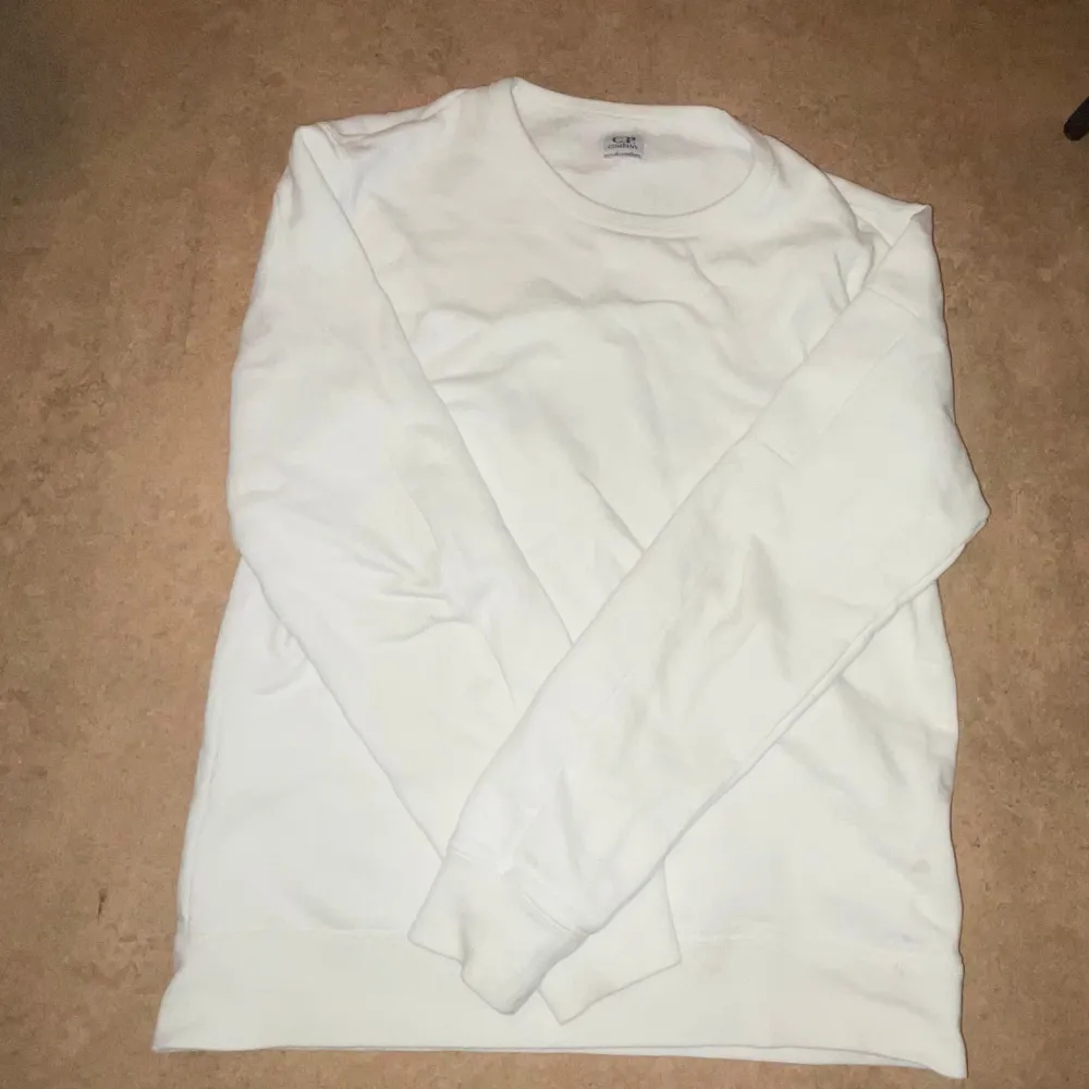 Snygg off-white tröja från Cp company med en lins på sidan av ärmen. Perfekt för en avslappnad look. Skick 9/10. Skriv vid minsta fundering.. Neuletakit & Villapaidat.
