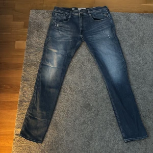 Blå Replay jeans anbass - Snygga blå jeans från Replay i modellen Anbass. De har en slim fit passform och är tillverkade av hållbar bomull. Perfekta för en stilren look med klassiska femfickor och dragkedja. Lite stora på mig som är 190 cm lång och väger 81 kg.