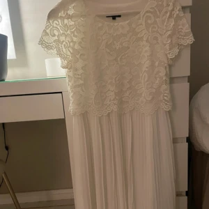 Vit spetsklänning - Elegant vit klänning med spetsöverdel och korta ärmar. Kjolen är plisserad och faller fint. Perfekt inför student eller skolavslutning. Använd en gång på en skolavslutning så i mycket bra skick