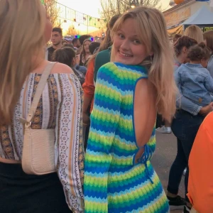 Färgglad stickad klänning💙💚 - Säljer en färgglad stickad klänning med ränder i blått, grönt och gult. Klänningen har en öppen rygg och långa ärmar, perfekt för en unik och iögonfallande stil. Den är tight och kort, vilket ger en snygg passform. Perfekt för dig som vill sticka ut!