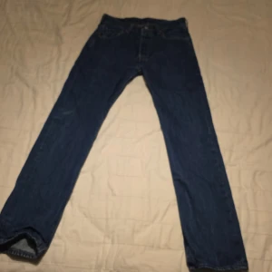 Levi's 501 jeans - Klassiska Levi's 501 jeans i blå denim. Dessa jeans har en rak passform och är tillverkade i slitstarkt bomullsmaterial. Perfekta för en avslappnad stil med fem fickor och knappgylf.