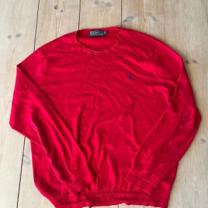 Röd tröja från Polo Ralph Lauren - Säljer en snygg röd tröja från Polo Ralph Lauren med deras ikoniska logga broderad på bröstet. Tröjan har långa ärmar och en klassisk rund halsringning. Perfekt för en stilren look!