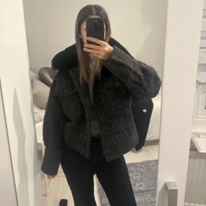 Grå pälsjacka med krage - Säljer en snygg grå pälsjacka med en fluffig krage. Jackan har en croppad passform och knappar framtill. Perfekt för kyliga dagar när du vill vara både varm och stilren. 🖤köpt för 2800! Ni får även med extra knappar som jag fick när jag köpte den! 