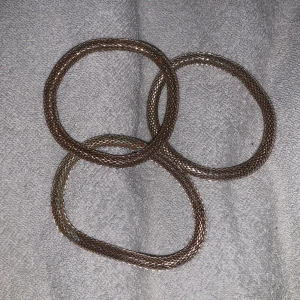 Guldiga armband i nätmönster - Säljer tre stilrena guldiga armband med ett elegant nätmönster. Perfekta för att ge en glittrig touch till din outfit. Armbanden är flexibla och lätta att bära.