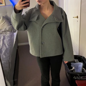 Grå kappa från Gina Tricot - Snygg grå kappa från Gina Tricot i storlek S. Jackan har en stilren design med stora knappar och en bred krage. Perfekt för kyligare dagar och ger en elegant touch till din outfit.