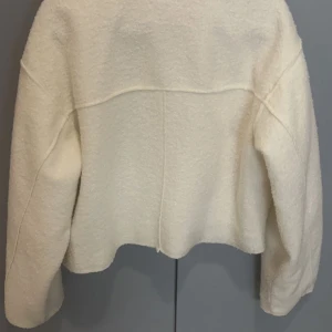 Vit teddyjacka med dragkedja - Säljer en mysig vit teddyjacka med dragkedja framtill och två stora fickor på bröstet. Jackan har en klassisk krage och är perfekt för kyligare dagar. Den är både stilren och bekväm, vilket gör den till ett måste i garderoben.