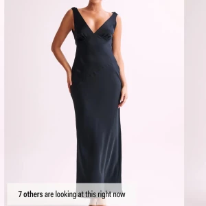 Svart långklänning med öppen rygg - Elegant svart långklänning med djup v-ringning och öppen rygg. Klänningen har en smickrande passform och är perfekt för speciella tillfällen. Tillverkad i satin och följsamt material som ger en lyxig känsla. Aldrig andvänd, endast testad med lapparna kvar 