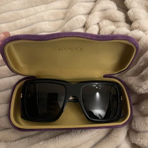 Svarta solglasögon från Gucci - Snygga svarta solglasögon från Gucci med en rektangulär form. De har en elegant design med märkets logotyp på skalmarna. Perfekta för att ge en stilren touch till din outfit.