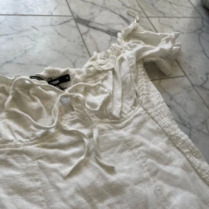 Kort Vit sommar klänning  - Säljer denna jättefina sommarklänningen ifrån bikbok. Storken är M men passar mig bra som i vanliga fall hsr XS-S. Ärmarna går att ha antingen på avlarna eller nedanför. Bysten knyts ihop med snöre och är justerbar. Baksidan är stretchiga vilket gör att den passar många och sitter fint. Endast andvänd vid ett tillfälle. Skriv gjärna vid funderingar. Inga fler bilder finns🩷