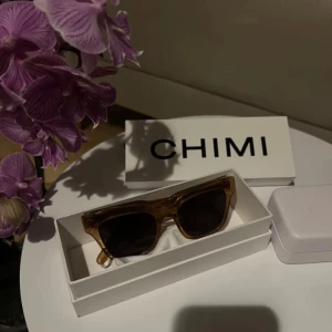 Solglasögon från CHIMI - Snygga solglasögon från CHIMI i modellen #005. De har en stilren design med en transparent persikofärgad båge och mörka linser. Perfekta för att ge din stil en extra touch. Har en liten skapa på glaset men inget som syns och inget man tänker på när man använder dem