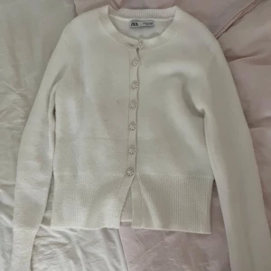 Tröja från Zara, vit med pärlknappar  - En vit tjocktröja från Zara som har vita pärlknappar, den är jätte varm, gosig och jättefin, ja säljer den för att den är för stor på mig. Den har används endast 2 ggr. jag köpte den för 400 kr för två år sen och nu säljer jag den för 250kr, men pris kan diskuteras. Köparen står för frakten 