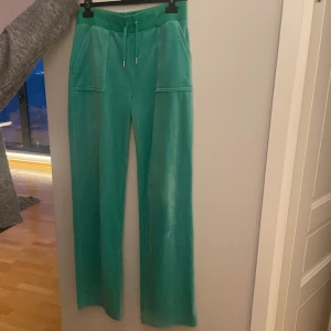 Gröna mjukisbyxor från Juicy Couture - Snygga gröna mjukisbyxor från Juicy Couture i mjukt material. Byxorna har en elastisk midja med snörning och fickor både fram och bak. Perfekta för en avslappnad stil. Inga defekter och de är i storlek M. Endast använda några gånger och byxorna köptes för 1200kr. Köp sker via ”köp direkt” knappen!🩷