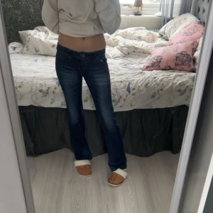 Mörkblå bootcut jeans från ONLY - Snygga mörkblå bootcut jeans från ONLY med låg midja. Perfekta för en avslappnad stil. Jeansen har en klassisk design med en lätt utsvängd passform som ger en retro känsla. Midje mått rakt över är 37, innerbenslängd är 79