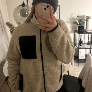 Beige teddyjacka från lager 157 - Beige teddyjacka från 157 med svarta detaljer. Är egentligen en herrmodell men jag har använt den, det enda är att den då är lite längre. 