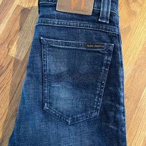 Mörkblå jeans från Nudie Jeans, modell High Kai - Snygga mörkblå jeans från Nudie Jeans med klassisk femficksdesign. De har en slim passform och är tillverkade i slitstarkt denim. Perfekta för en stilren look och passar och killar..