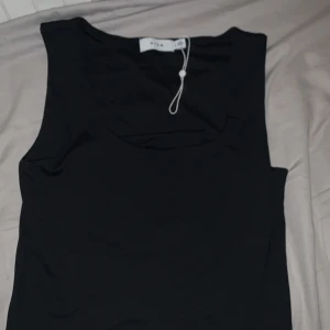 Svart linne från VILA - Helt ny och oanvänd snygg svart linne från VILA i ett mjukt och bekvämt material. Perfekt för en stilren look. Toppen har en enkel design som gör den lätt att matcha med olika outfits. Dessutom har den mer tjockare band.