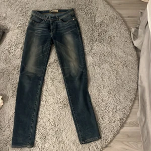 Levi's Revel Demi Curve Skinny Jeans - Snygga Levi's Revel Demi Curve skinny jeans i en klassisk blå färg. De har en smickrande passform med skinny stil och är perfekta för en trendig look. Jeansens design inkluderar de ikoniska bakfickorna och en bekväm midja.