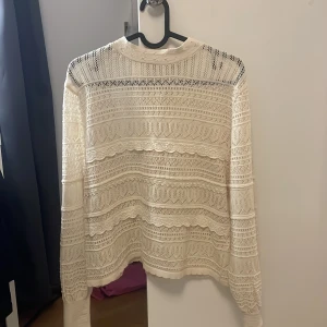 Vit spetsblus - Säljer en elegant vit spetsblus med långärmad design. Blusen har ett vackert mönster och en rund halsringning. Perfekt för att ge en romantisk touch till din outfit.