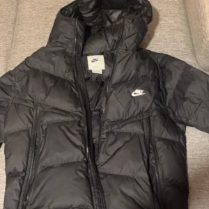 Svart dunjacka från Nike - Säljer en svart dunjacka från Nike med Storm-FIT teknologi. Jackan har en huva och dragkedja framtill. Perfekt för kyliga dagar. Original pris 2000 kr kan diskuteras pris 