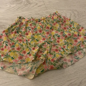 Blommiga shorts från Zara Kids - Säljer ett par färgglada shorts från Zara Kids med blommigt mönster i rosa, gul och grön. Perfekta för sommarens varma dagar! 🌸