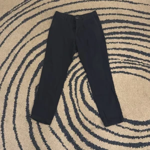 Mörkblå byxor från GANT - Snygga svarta byxor från GANT med dragkedja och knapp framtill. Byxorna har en klassisk design och är perfekta för en stilren look. Tillverkade i ett bekvämt material som passar till många tillfällen. Nypris: 700kr. Använt väldigt försiktigt. Skriv vid minsta fundering!