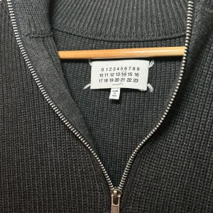 Maison Margiela Half-zip M  - Säljer en stilren grå stickad tröja från Maison Margiela. Tröjan har en praktisk dragkedja framtill och långa ärmar. Perfekt för kyligare dagar. Storlek 46/M. Varan är i så gott som nytt skick. Endast använd en gång 