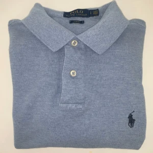 Blå pikétröja från Ralph Lauren - Snygg blå pikétröja från Ralph Lauren i storlek L fast sitter som M. Väldigt bra skick 9/10 inga defekter. Nypris 1400 och mitt pris 299. 