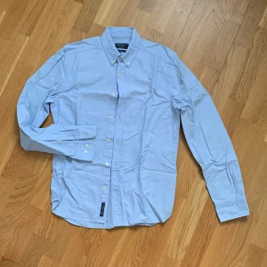 Ljusblå skjorta - Klassisk modell, buttondown, slimfit. Helt oanvänd pga för liten. Skönt bomullstyg, passar alla. 