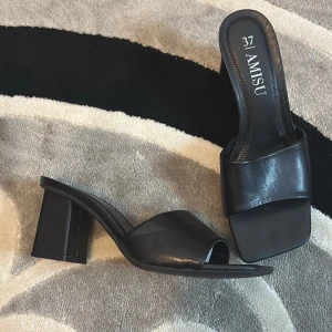 Svarta klackskor från Amisu - Snygga svarta klackskor från Amisu med öppen tå och bred rem över foten. Perfekta för en stilren look.