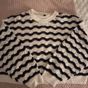 Marinblå-vit stickad tröja från H&M Divided - Säljer en snygg blåvit stickad tröja från H&M Divided med vågigt mönster. Tröjan har en rund halsringning och är lite cropped. Perfekt för en stilren look! Storlek L men passar bra på XS faktiskt. Pris går att diskuteras!
