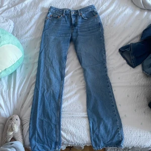 Blå jeans  - Snygga blå jeans med klassisk femficksdesign och knappgylf. Perfekta för en avslappnad stil. De har en rak passform och är tillverkade i slitstarkt denim.