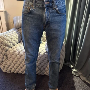 Nudie Jeans, Grim tim - Säljer ett par klassiska blå jeans från Nudie Jeans. Riktigt snygga och fungerar till allt. Midjan är 28 men passar mig som brukar ha 30 i midja. 