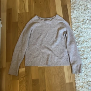 Beige stickad tröja från Vero Moda - Mysig beige/rosa stickad tröja från Vero Moda. Den  har en bekväm passform. Tröjan har långa ärmar och en klassisk rund halsringning. Den är dock lite nopprig.