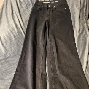 Svarta Tower Wide jeans - Snygga svarta Tower Wide jeans med hög midja och breda ben. Perfekta för en trendig look. Storlek 27 med längd 32. Passar utmärkt till både sneakers och klackar.