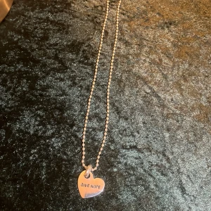 Halsband med hjärthänge - Snyggt halsband med ett hjärthänge i silverfärg. Hänget har texten 'GIVE HOPE' ingraverat. Kedjan är av kulmodell och ger en modern touch. Perfekt för att bära som ett dagligt statement.