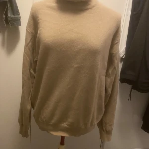 Beige polotröja - Mysig beige polotröja med långa ärmar och ribbade muddar. Perfekt för kyliga dagar och en stilren look.