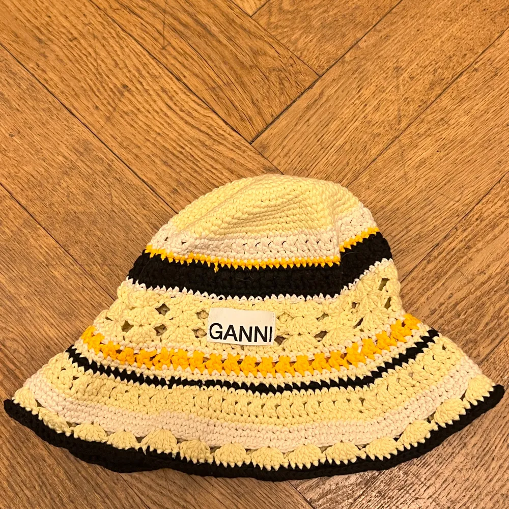 Snygg randig hatt från Ganni i bomull med gula, svarta och vita ränder. Perfekt för sommaren med sin lätta och luftiga design. Hatten har en bred kant och ett broderat Ganni-märke framtill.. Asusteet.