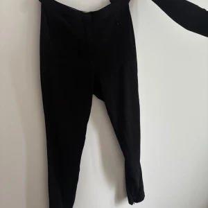 Svarta byxor från By Malene Birger - Snygga svarta byxor från By Malene Birger. De har en elegant design med en smal passform och dragkedja vid bensluten. Perfekta för en stilren look.