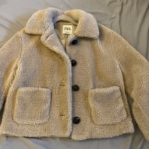Beige teddyjacka från Zara - Mysig beige teddyjacka från Zara med stora knappar och två framfickor. Perfekt för kyliga dagar med sin fluffiga och varma design. Jackan har en klassisk krage och långa ärmar!! 💋🙏🏽