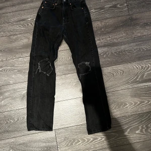 Svarta jeans från Gina  - Säljer ett par svarta jeans från Gina tricot med coola slitningar på knäna. De har en klassisk femficksdesign och knappgylf. Perfekta för en avslappnad stil.