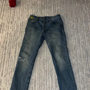 Levi's Super Mario jeans - Unika och sällsynta Levi's jeans med Super Mario-tema. Dessa blå jeans har broderade detaljer och färgglada knappar. Perfekt för den som vill sticka ut med en retro touch.