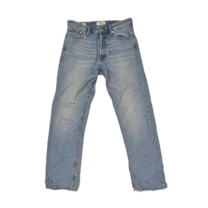 Blå jeans från Jack & Jones - Säljer ett par klassiska blå jeans från Jack & Jones. De har en straight passform och är tillverkade i slitstarkt denim. Perfekta för en avslappnad stil.