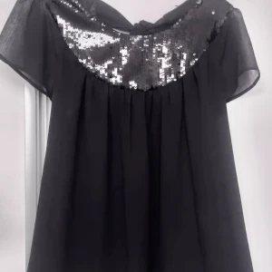 Grön paljettklänning med djup v-ringning - Oanvänd. Snygg grön klänning täckt av glittrande paljetter och ett iögonfallande mönster. Den har en djup v-ringning och dragkedja i ryggen. Perfekt för en festlig kväll!